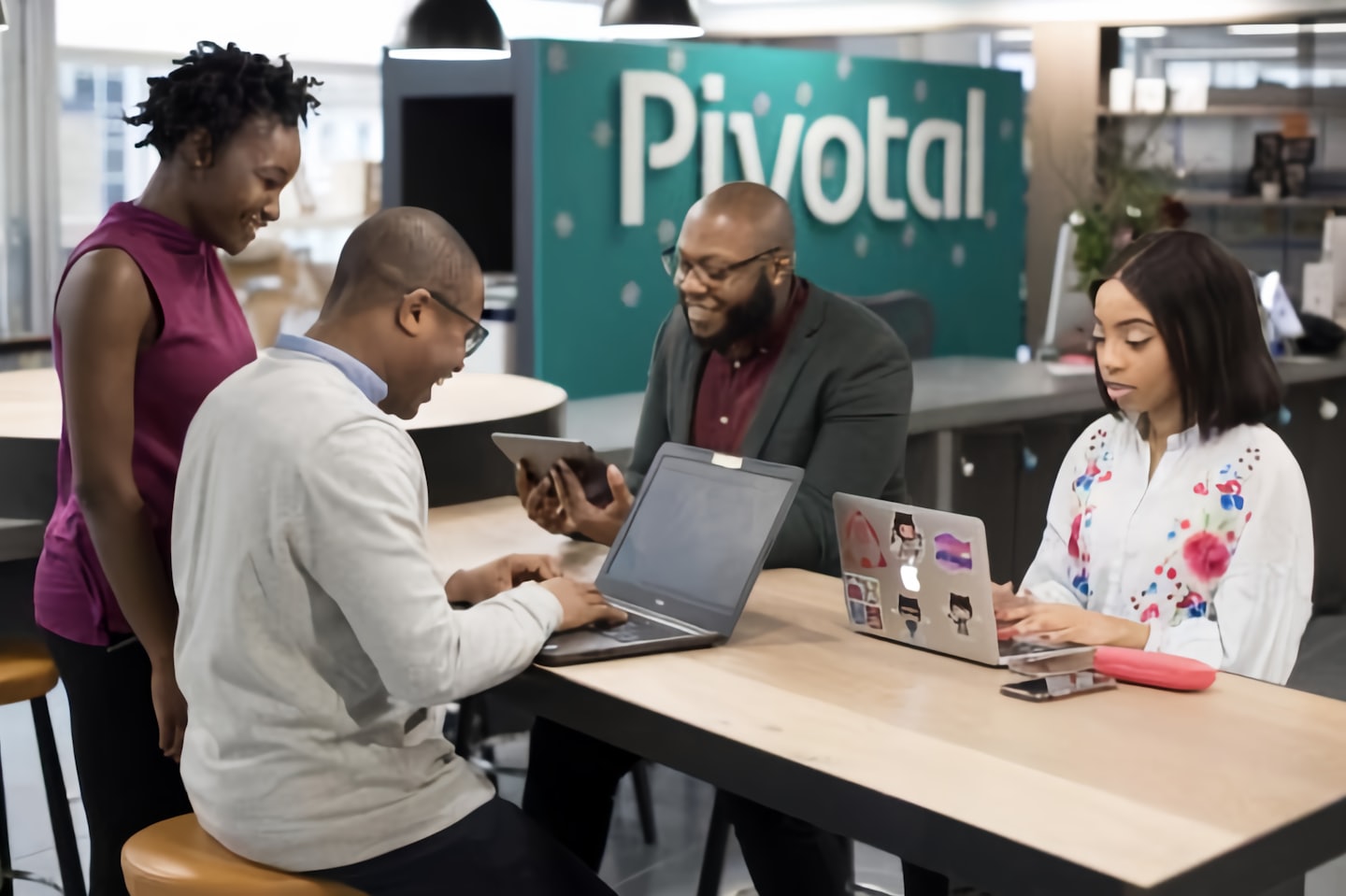 Four professionals collaborating around a table with laptops.