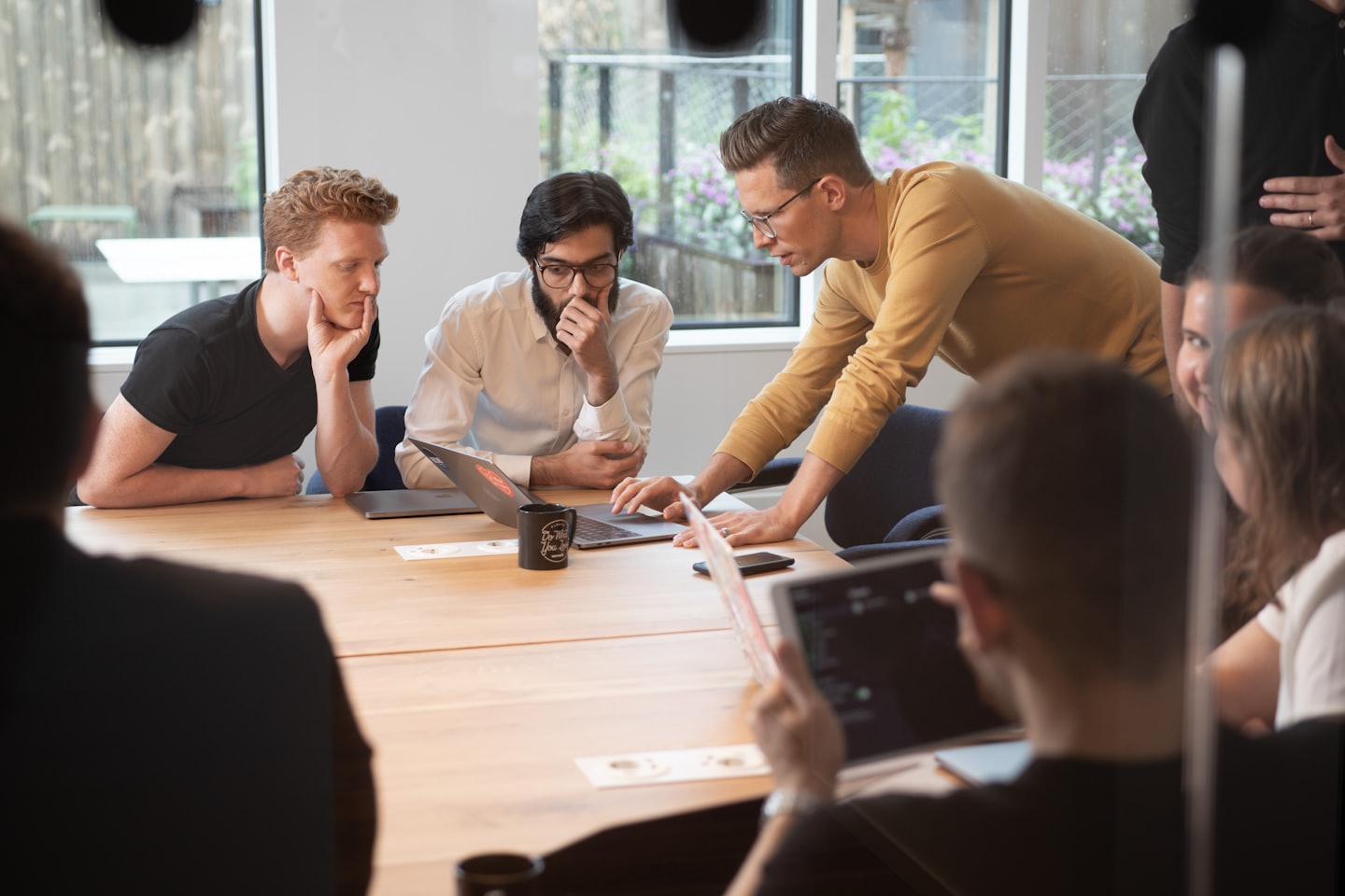 Professionals collaborating around a conference table with laptops.